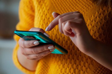 Cep telefonu kullanan, el ele tutuşan bir kadın.