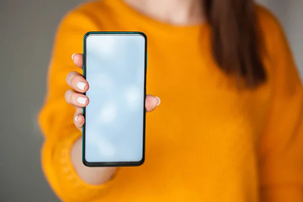 Woman hold mobile phone screen mocap in hands in the orange sweater