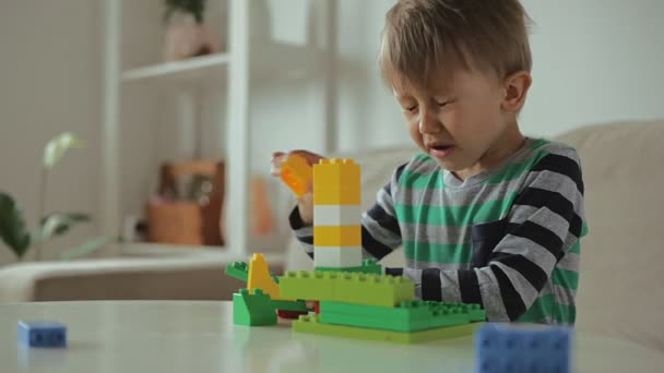 Éternuement d'enfant jouant avec le constructeur coloré de blocs de plastique de construction à la maison — Video