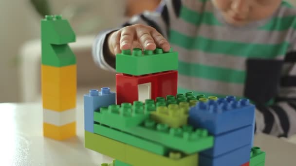 Дитина грає з барвистим конструктором будівельних пластикових блоків крупним планом вдома — стокове відео