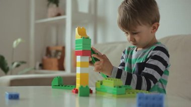 Child playing with colorful building plastic blocks constructor at home, tower falls, fail