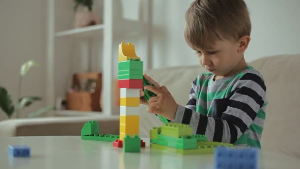 Дитина грає з барвистим конструктором будівельних пластикових блоків вдома, вежа падає, невдача — стокове відео