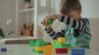 Evde renkli bina plastiği bloklarıyla oynayan çocuk