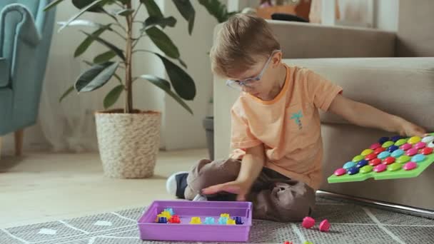 Criança brincando com brinquedo jogo educacional sentado no chão em casa. Desenvolve habilidades motoras finas — Vídeo de Stock