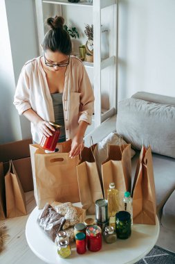 Kadın bağış için yiyecek paketliyor. Kese kağıdına, fotokopi alanı da boş.