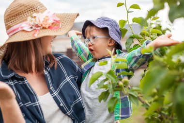 Mother and child near tree, gardening in the backyard garden