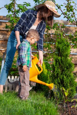Çocuk ve anne sulama tenekesi bahçedeki sebze bahçesini suluyor.