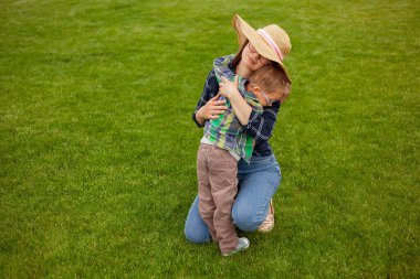 Mother and child hugging sitting on the lawn in the backyard