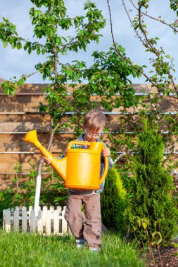 Çocuk sulama konservesi bahçedeki sebze bahçesini suluyor.