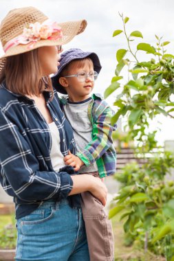 Mother and child near tree, gardening in the backyard garden