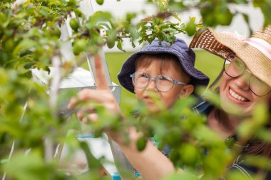 Mother and child near tree, gardening in the backyard garden