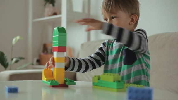 Enfant jouant avec le constructeur coloré de blocs en plastique de construction à la maison — Video