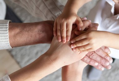 Büyükbaba, kızı ve küçük torunu birlikte avuç içi ve el yığını oluşturuyorlar. Mutlu aile birlikteliği. Mutlu aile ve yaşlı ebeveynler konseptine destek.