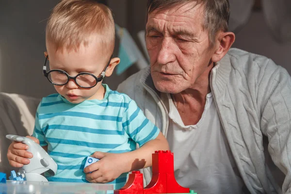老爷爷和他的小孙子玩塑料块 — 图库照片