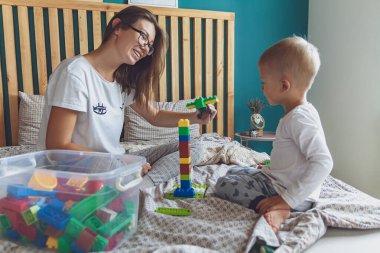Anne ve çocuk yatak odasında plastik bloklu bir yatakta birlikte oynuyorlar.