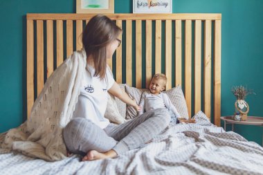 Anne ve çocuk yatak odasında, yatakta, battaniyenin altında eğleniyorlar.