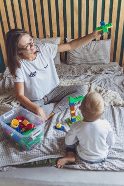 Anne ve çocuk yatak odasında plastik bloklu bir yatakta birlikte oynuyorlar.