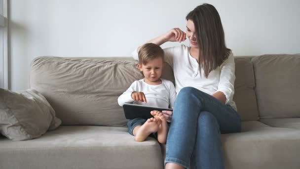 家庭母亲和孩子们坐在家里的沙发上用平板电脑 — 图库视频影像