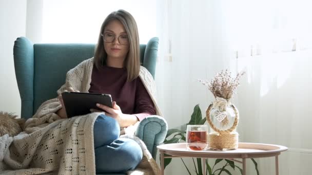 Jovem Mulher Óculos Usando Tablet Digital Bebendo Chá Sentada Poltrona — Vídeo de Stock