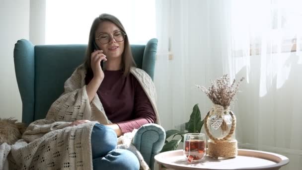 Młoda Kobieta Okularach Rozmawiająca Przez Telefon Komórkowy Przykrywająca Przytulną Kratę — Wideo stockowe