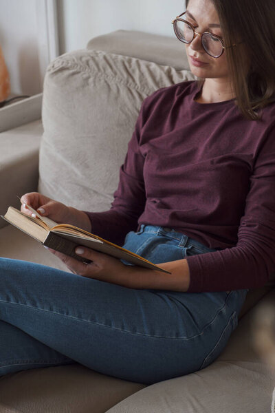 Woman reading book and relaxing sitting in sofa at home