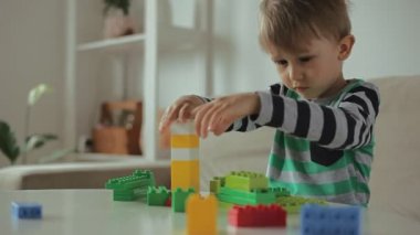 Evde renkli bina plastiği bloklarıyla oynayan çocuk