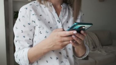 Kadın evde cep telefonundan mesaj gönderen elleri kapalı.