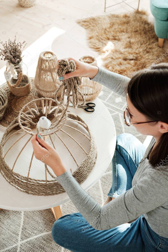 Woman makes handmade diy lamp from jute rope at home