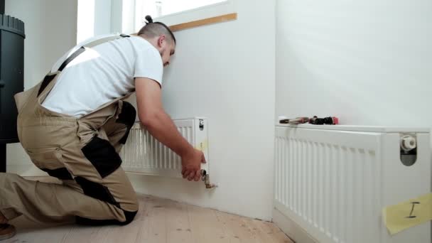 Plumber installing new steel hot water central heating radiator — Stock Video