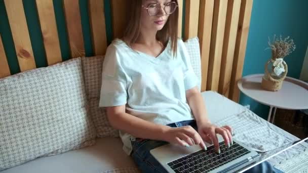 Giovane donna che digita rapidamente sulla tastiera utilizzando il computer portatile per lavorare, sdraiato sul letto in camera da letto, orari flessibili e lavoro a distanza. — Video Stock