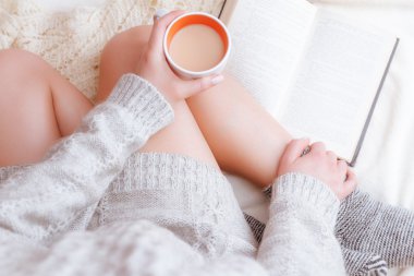 Kadın kitap ve bir fincan çay ile