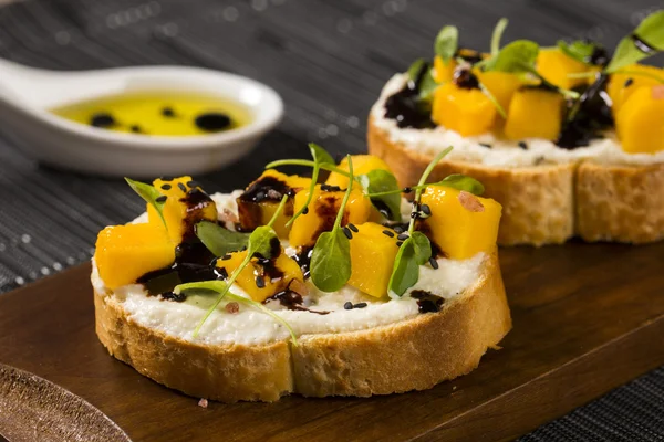 Bruschetta com manga picada, agrião, manjericão e queijo de cabra em f — Fotografia de Stock