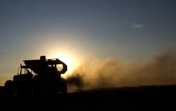 Máquina rural que trabalha no campo agrícola ao pôr do sol . — Fotografia de Stock