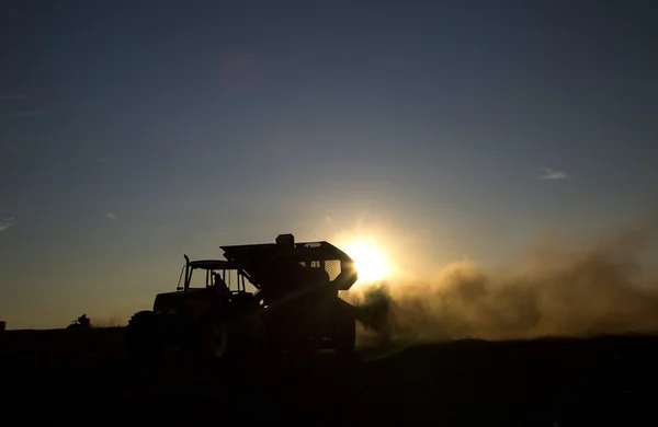 Máquina rural que trabalha no campo agrícola ao pôr do sol . — Fotografia de Stock