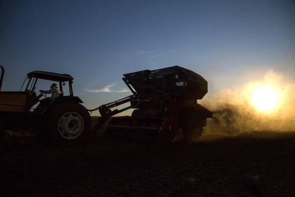 Máquina rural que trabalha no campo agrícola ao pôr do sol . — Fotografia de Stock