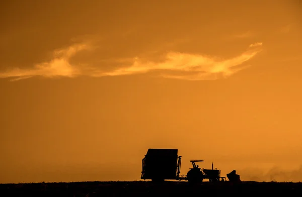 Máquina rural que trabalha no campo agrícola ao pôr do sol . — Fotografia de Stock