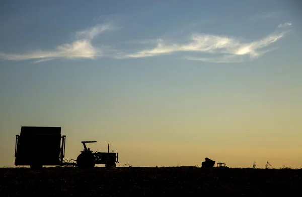 Máquina rural que trabalha no campo agrícola ao pôr do sol . — Fotografia de Stock