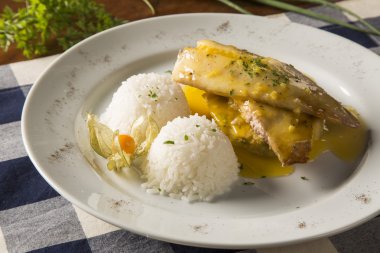 Kızarmış tilapia ile pirinç beyaz tabakta servis.