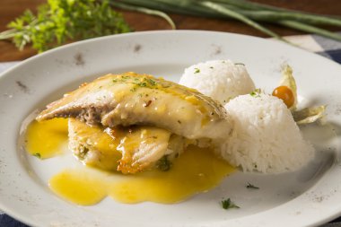 Kızarmış tilapia ile pirinç beyaz tabakta servis.