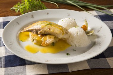 Kızarmış tilapia ile pirinç beyaz tabakta servis.