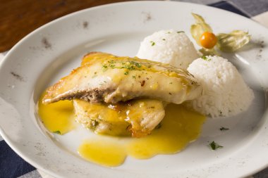 Kızarmış tilapia ile pirinç beyaz tabakta servis.