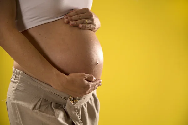 Portrait of 9 months pregnant woman over yellow background