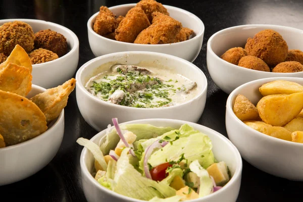 Mixed brazilian snacks, including pastries, fried chicken, salad — Stock Photo, Image