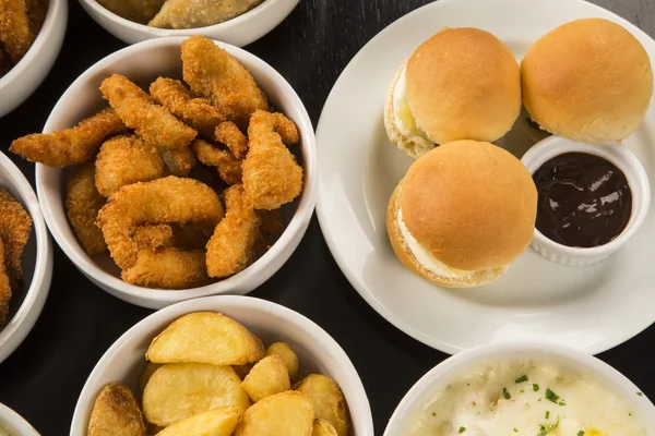 Mixed brazilian snacks, including pastries, fried chicken, salad — Stock Photo, Image