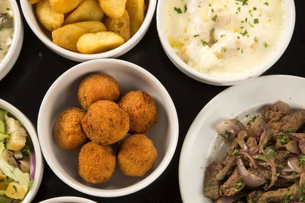 Mixed brazilian snacks, including pastries, fried chicken, salad — Stock Photo, Image