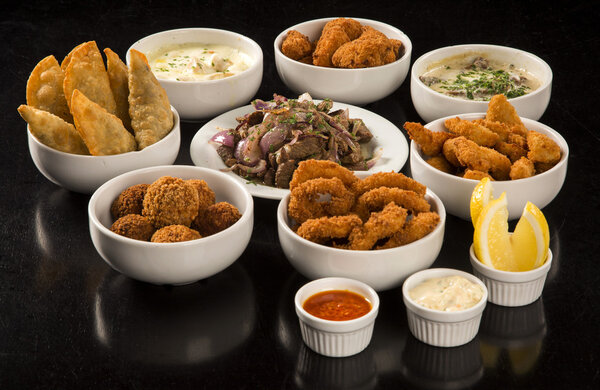 Mixed brazilian snacks, including pastries, fried chicken, salad