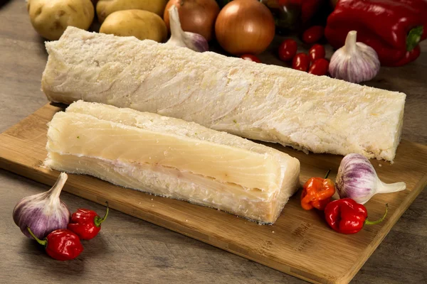 Salted codfish on the wooden table with ingredients — Stock Photo, Image