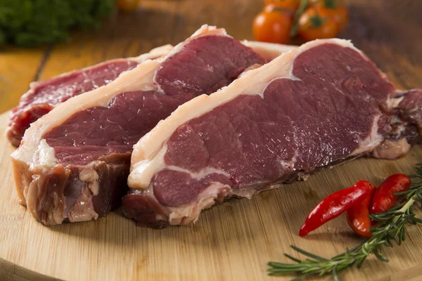Selezione di carne cruda su tagliere in legno . — Foto Stock