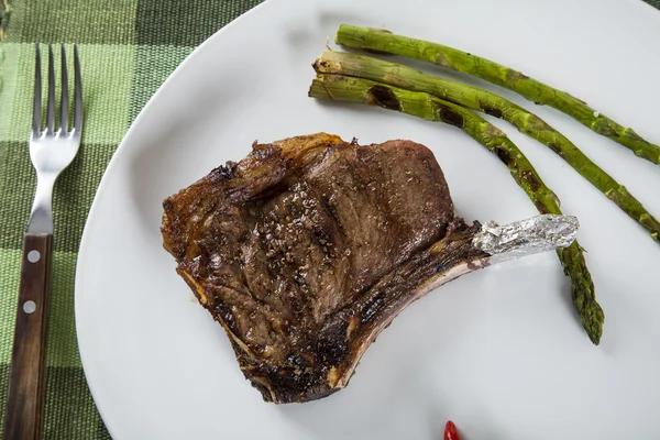 Costelas de carne grelhadas na placa branca com cebolinha de tomates e h escuro — Fotografia de Stock