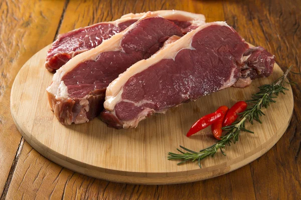 Carne cruda: filete de ternera fresca con ajo y materia verde sobre madera — Foto de Stock